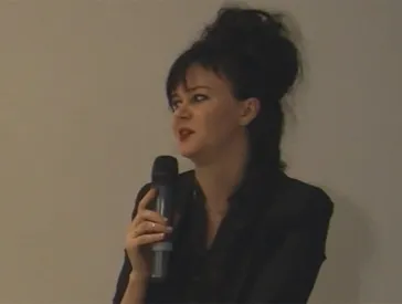 Frau spricht mit Mikrofon in der Hand.