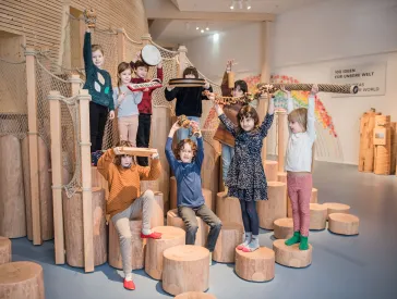 Neun Kinder stehen im Klanglabor im Kindermuseum ANOHA des Jüdischen Museums und halten Gegenstände in der Hand.