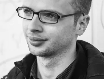 Schwarz-Weiß-Porträt eines jungen Mannes mit Brille im Halbprofil
