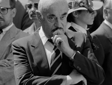 An older man in a suit and kippa looks thoughtfully into the camera.