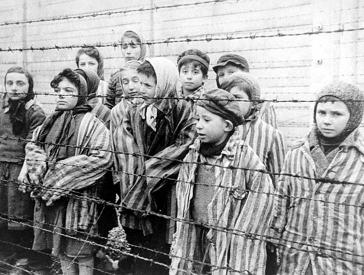 Schwarz-weiß Fotografie mit Kindern in Kleidung der Konzentrationslager in Auschwitz hinter einem Stacheldrahtzaun stehend