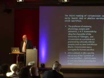 Mann am Rednerpult, hinter ihm eine Folie seiner Pr&auml;sentation.