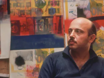 A middle-aged man sits in a studio.