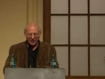 Mann steht an einem Rednerpult und h&auml;lt einen Vortrag.