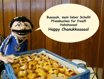 Handpuppe die hinter einer Kiste gefüllt mit Pfannkuchen steht, dazu eine Sprechblase.