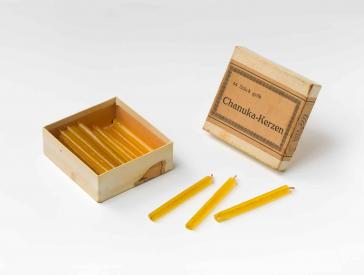 An old, opened cardboard-box with yellow candles.