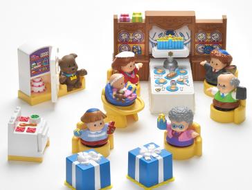 Spielzeugfiguren sitzen an einem gedeckten Tisch.