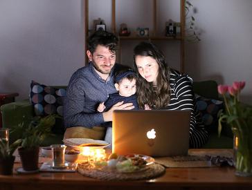 Ein Mann, ein Kind und eine Frau sitzen vor einem Laptop