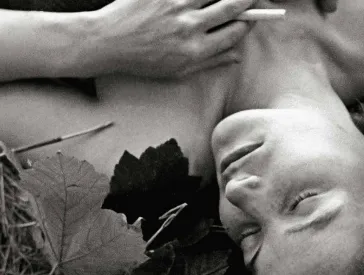 Schwarz-Weiß-Fotografie einer Frau mit geschlossenen Augen, die auf einer Wiese liegt