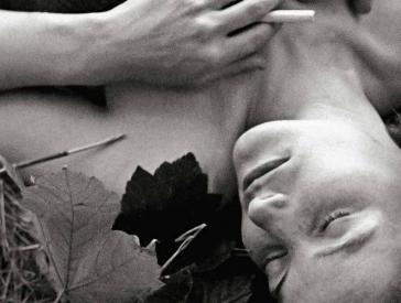 Schwarz-Weiß-Fotografie einer Frau mit geschlossenen Augen, die auf einer Wiese liegt