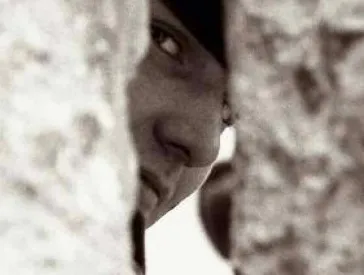 Ein Mensch schaut durch eine löcherige Mauer