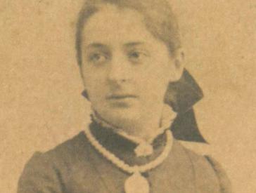 Historische Schwarz-Weiß-Porträtfoto einer jungen Frau in hochgeschlossenem Kleid.