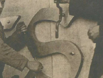 Historisches Foto, das zeigt, wie zwei Männer eine Inschrift am Berliner Reichstag anbringen.