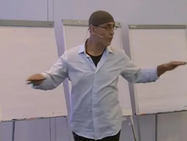 Mann vor drei Flipcharts moderiert einen Workshop.