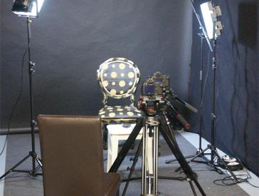 Der leere Stuhl bei den Dreharbeiten zwischen zwei Scheinwerfern und hinter einer Kamera.