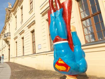 Skulptur, die Superman zeigt, wie er aus senkrechtem Flug auf dem Boden aufprallt