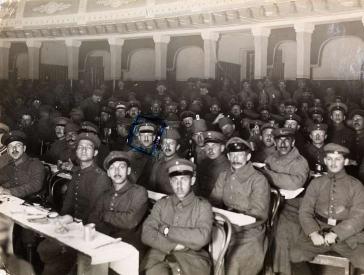 Zuschauerreihen eines Theatersaals besetzt mit Männern in Uniform.