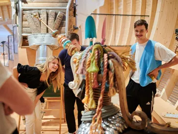 Drei Erwachsene begutachten eine Tier-Skulptur.