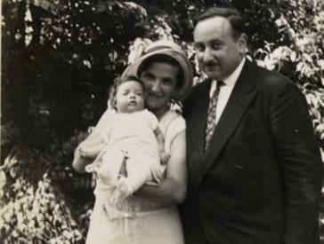 Schwarz-weiß-Foto: ein Mann neben einer Frau, sie hält ein Baby in die Kamera.
