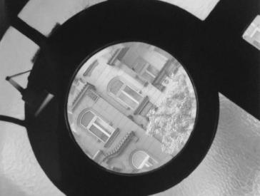 Black-and-white photograph: View of the buildings opposite through a transom window