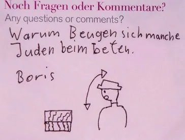 Ein pinker Post-it-Zettel beschriftet mit „Warum Beugen sich manche Juden beim beten?“