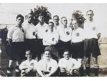 Schwarz-Wei&szlig;-Foto einer Fu&szlig;ballmannschaft mit wei&szlig;en Trikots und dunklen Hosen.