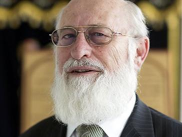Elderly man in a suit with glasses and full beard.