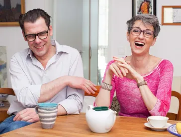 Mann und Frau sitzen lachend am Tisch