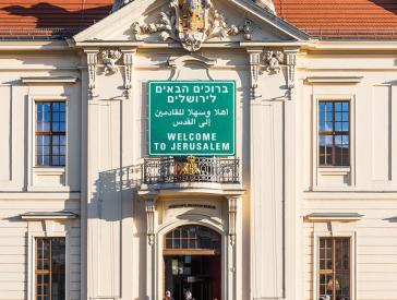 Auf dem Farbfoto ist die Fassade des Jüdischen Musuems Berlin mit dem einem Verkehrsschild nachempfundenen Schild mit der Aufschrift Welcome to Jerusalem in den Spachen Englisch, Arabisch und Hebräisch zu sehen.