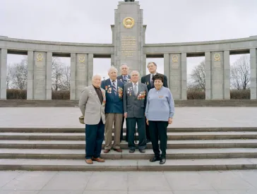  Old people stand on the stairs in front of a monument
