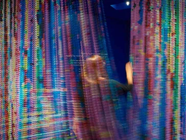 Colorful curtain in motion through which a person passes.