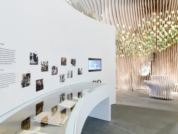 white room with display case with exhibits and photos on the wall