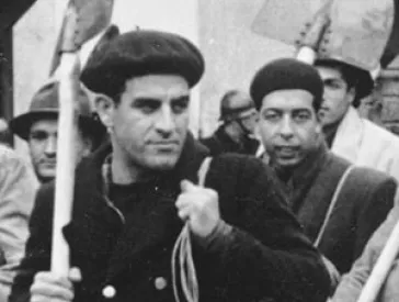 A group of men with luggage and spades.