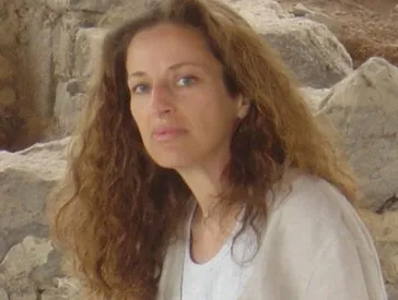A woman on a mosaic floor in front of ruins.
