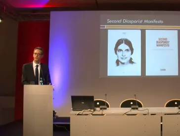 Mann am Rednerpult spricht vor Publikum.