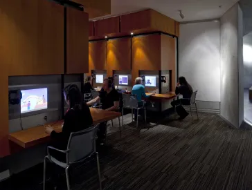Interior view of the Rafael Roth Learning Center in the basement of the Jewish Museum Berlin. Several people are looking at screens.