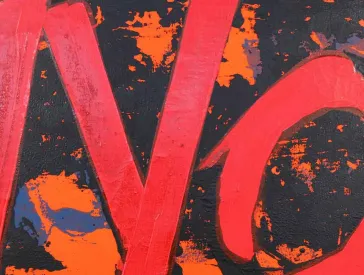 In Rot steht &raquo;NO&laquo; auf schwarz-orangem Grund