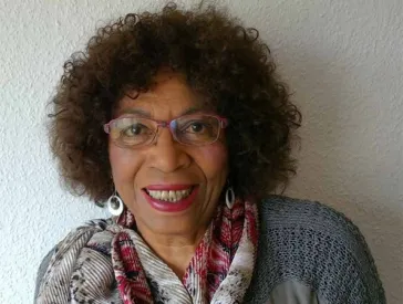 Portr&auml;t einer Frau mit Brille, die l&auml;chelt und direkt in die Kamera schaut
