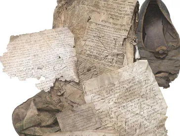 Verschiedene zerknitterte Schriftstücke mit hebräischen Buchstaben, ein Schuh und eine Tasche