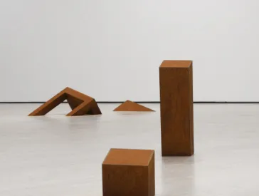 In einem leeren Raum verteilte Objekte aus gerostetem Eisen, sie wirken teilweise wie eingesunken