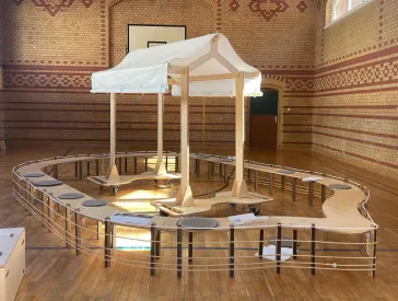 Aus Holzelementen zusammengesteckte Arche in einer Turnhalle.