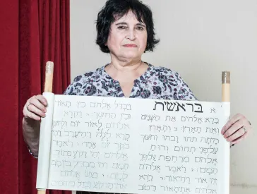 Eine Frau h&auml;lt eine selbstgebasteltet Tora-Rolle in H&auml;nden