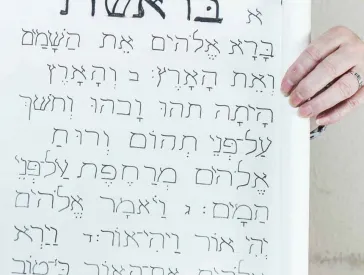 Eine Frau hält eine selbstgebasteltet Tora-Rolle in Händen.