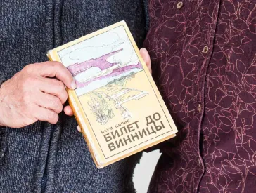 Älterer Herr und ältere Dame halten gemeinsam ein Buch in Händen.