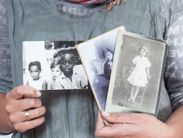 Eine Person hält auf Brusthöhe mehrere Schwarz-Weiß-Fotos in die Kamera, Gesicht und Beine der Person sind nicht zu sehen