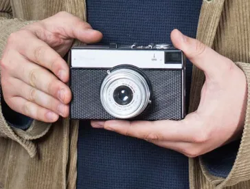 Zwei Hände halten einen analoge Kamera aus den 1980er Jahren