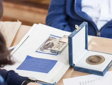 Several people are sitting around a table on which memorabilia and a recording device are lying.