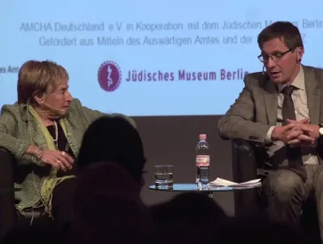 Eine Frau und ein Mann auf einem Podium.