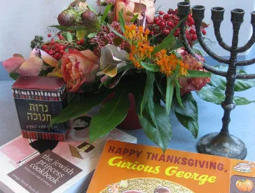 Eine Menora, ein Blumenstrauß und das Buch „Curious George“.