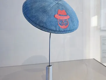 Kippa made of denim and with embroidery on a metal stand.
